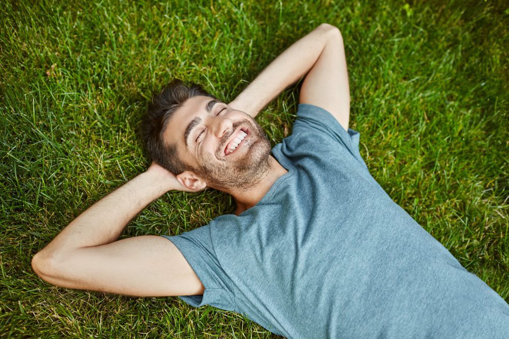 emociones positivas hombre caucasico barbudo hermoso joven camiseta azul tirado hierba sonriendo dientes riendo relajandose afuera manana verano expresion cara feliz 2